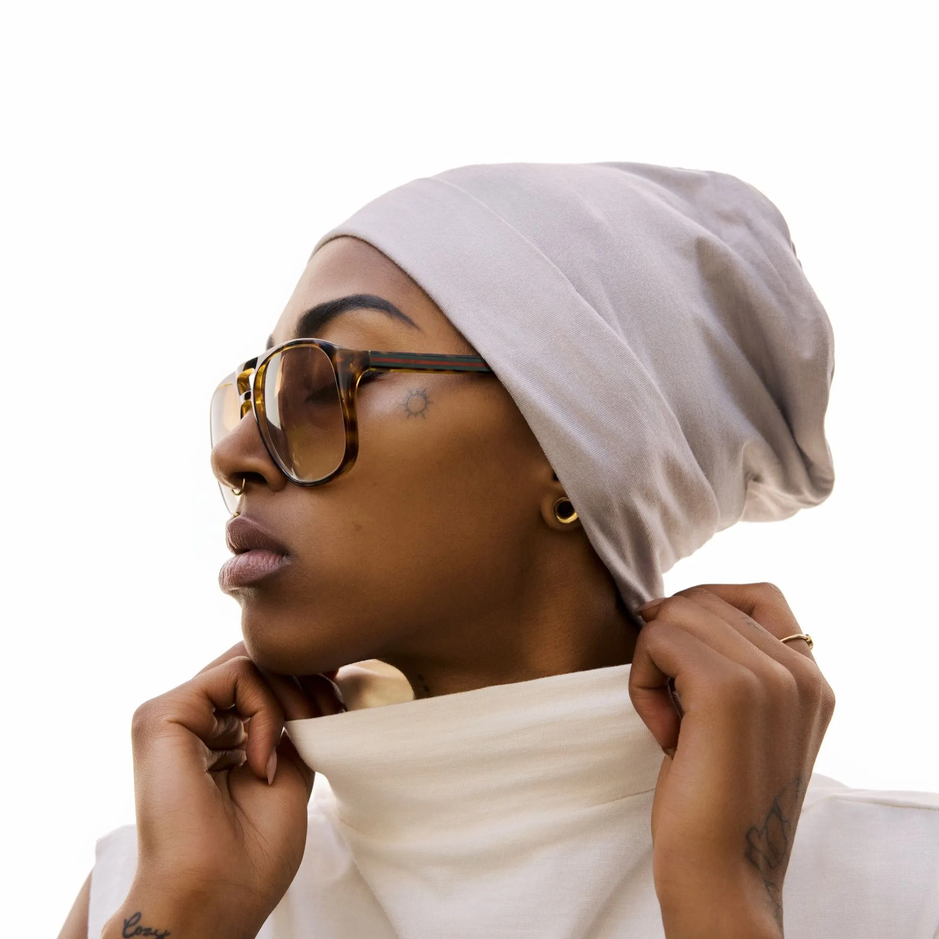 Frau fährt sich sanft über ihr Kopftuch, entspannter Gesichtsausdruck