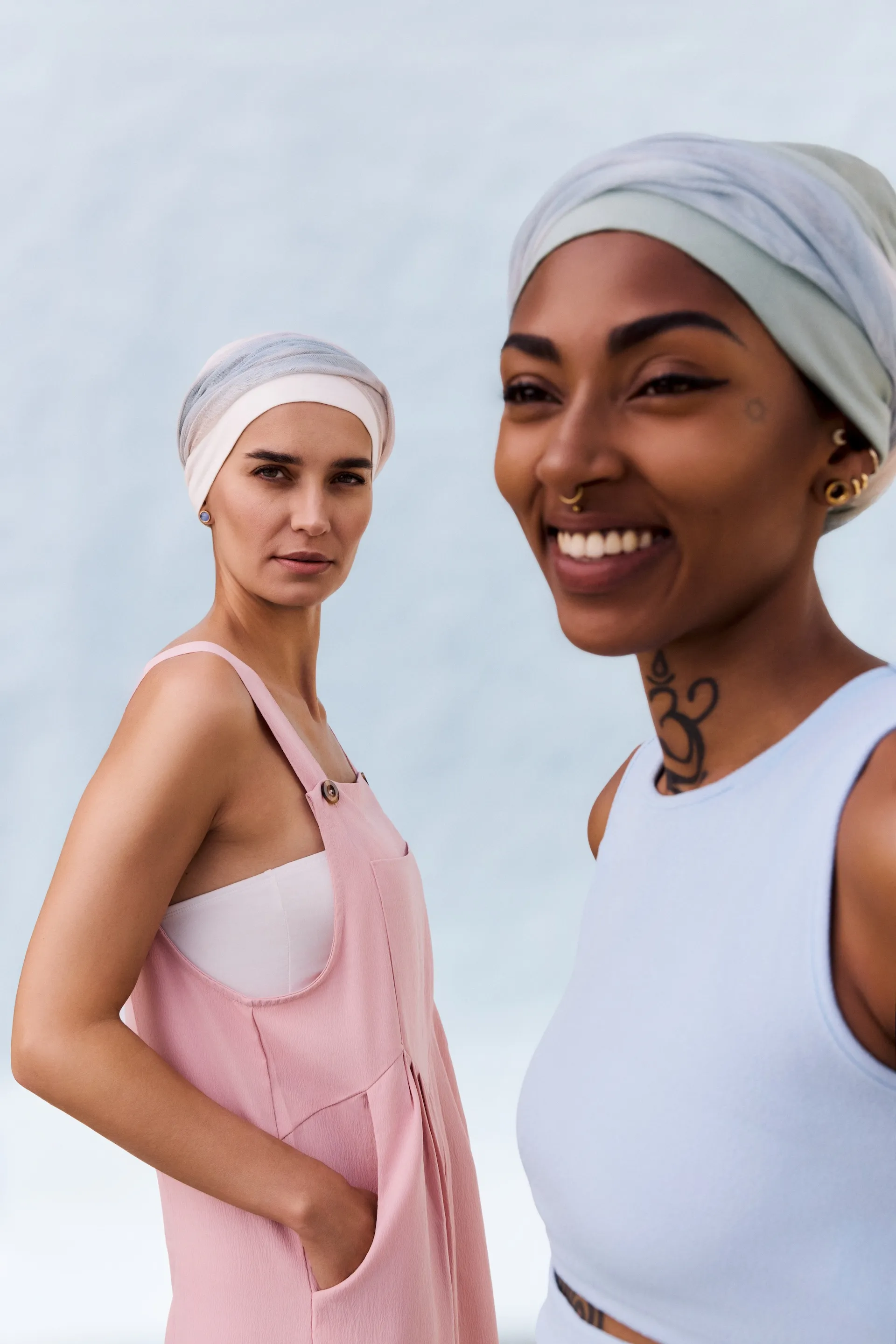 Lächelnde Frau im Studio des Perückenstylisten, im Hintergrund Perücken und Kopfbedeckungen